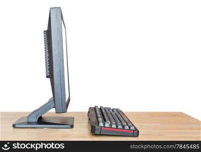 side view of computer display with cut out screen and keyboard on wooden table isolated on white background