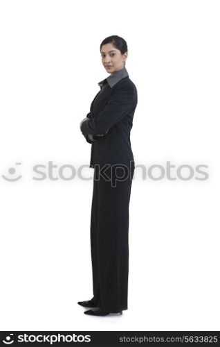 Side view of confident businesswoman with arms crossed standing against white background