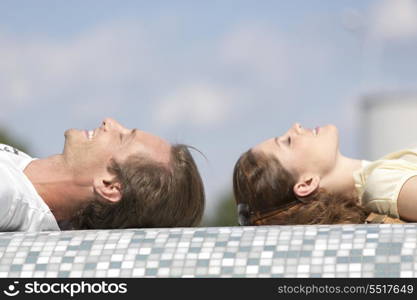 Side view of couple relaxing on mosaic wall