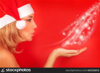 Side view of cute blond Santa girl blowing snowflakes from hand isolated on red background, celebration of Christmas time holidays