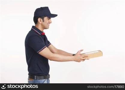 Side view of delivery man giving package against white background