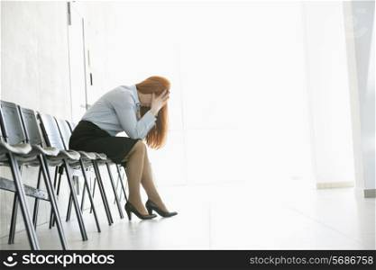 Side view of exhausted businesswoman sitting on chair in office