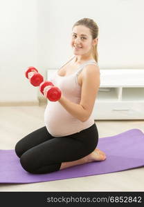 Side view of expectant mother exercising with dumbbells