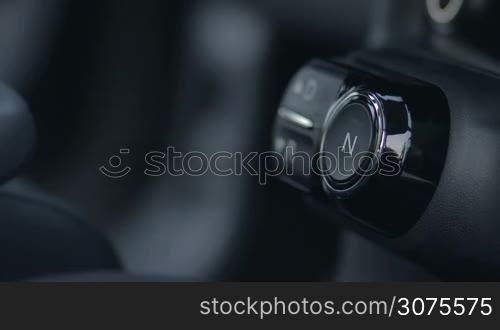 Side view of female car driver&acute;s hand pushing gearbox drive button on car&acute;s dashboard to start driving