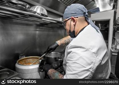 Side view of female chef working in commercial kitchen. High quality photography. Side view of female chef working in commercial kitchen