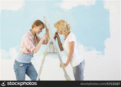 Side view of female friends painting together in new home