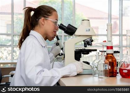 Side View Of Female Scientist Looking Through Microscope At Laboratory