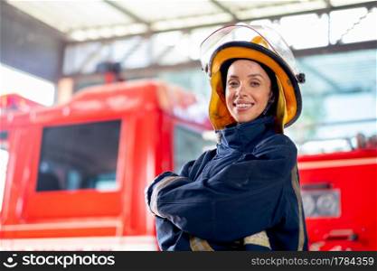 Side view of fireman or firefighter woman with protective clothes stand with confidence action and smile in front of fire truck. She also smile with happy and love to work with this job.