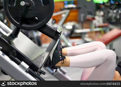 Side view of fit young sportswoman flexing her leg’s muscles on exercise machine at the gym. High quality photo.. Side view of fit young sportswoman flexing her leg’s muscles on exercise machine at the gym.