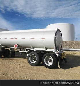 Side view of fuel tanker truck with fuel tank farm in background.