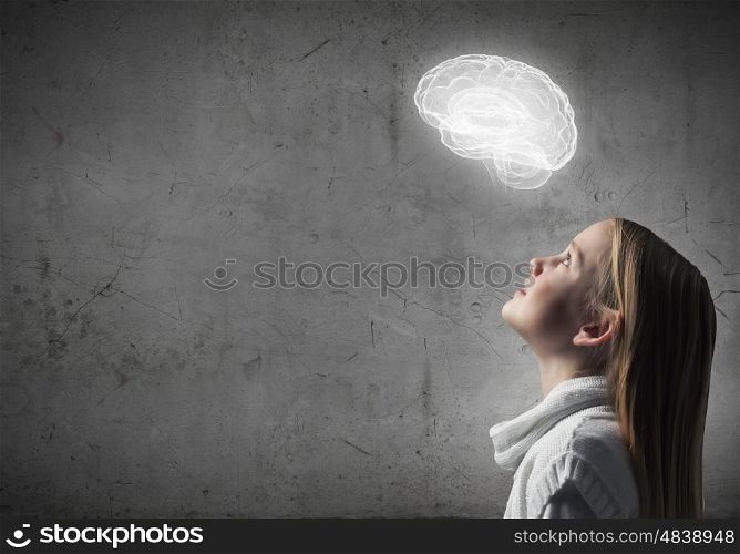 Side view of girl of school age looking at brain above
