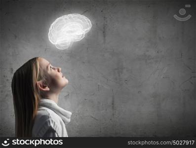 Side view of girl of school age looking at brain above