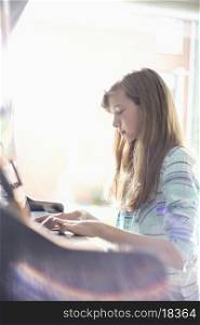Side view of girl playing piano at home