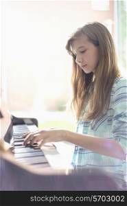 Side view of girl playing piano at home
