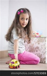 Side view of girl playing with toy car at home