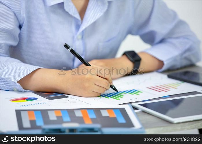 Side View Of Graph Papers On Table and business people writing on paperwork