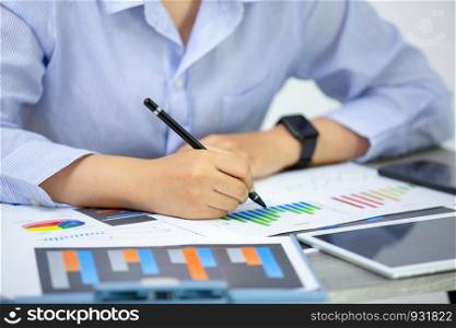 Side View Of Graph Papers On Table and business people writing on paperwork
