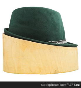 side view of green tyrolean felt hat on linden wood hat block isolated on white background