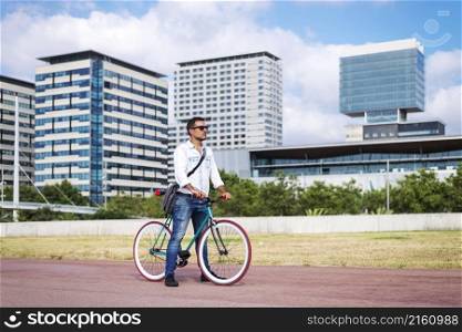 Side view of handsome young male looking away while riding on his bicycle outdoors.