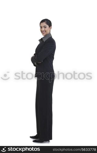Side view of happy businesswoman with arms crossed standing against white background