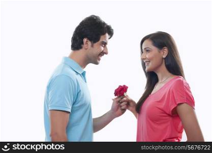 Side view of happy man giving rose to woman over white background