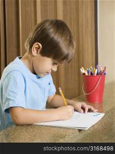 Side view of Hispanic boy concentrating on homework.