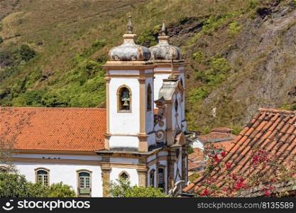 Side view of historic church in baroque and colonial style from the 18th century amid the hills and vegetation of the city Ouro Preto in Minas Gerais, Brazil. Side view of historic church in baroque and colonial style from the 18th century amid the hills and vegetation
