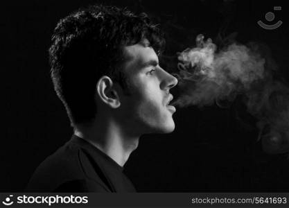 Side view of Indian man smoking against black background
