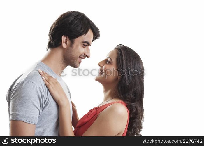 Side view of loving couple looking at each other against white background