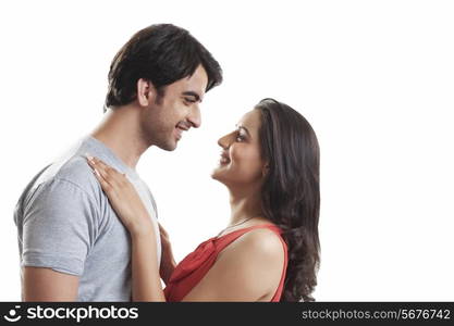 Side view of loving couple looking at each other against white background