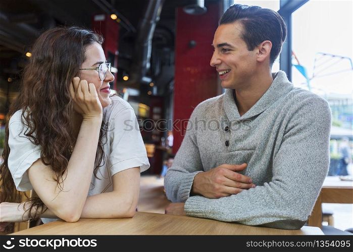 Side view of loving couple looking at each other sitting in a coffee shop