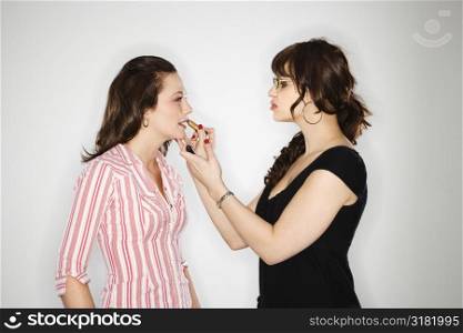 Side view of makeup artist putting lipstick on young Caucasian woman.