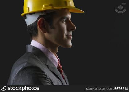 Side view of male architect wearing hardhat against black background