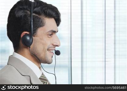 Side view of male customer service representative wearing headset in office
