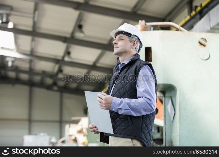 Side view of male supervisor holding clipboard in metal industry