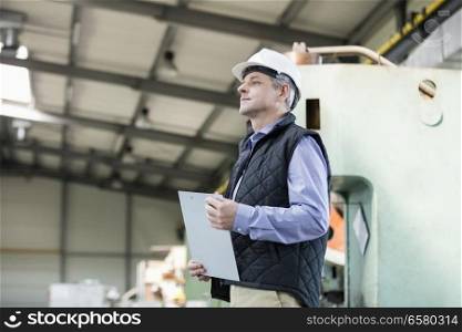 Side view of male supervisor holding clipboard in metal industry