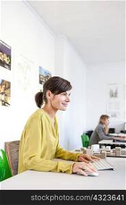 Side view of mature woman in office using computer smiling