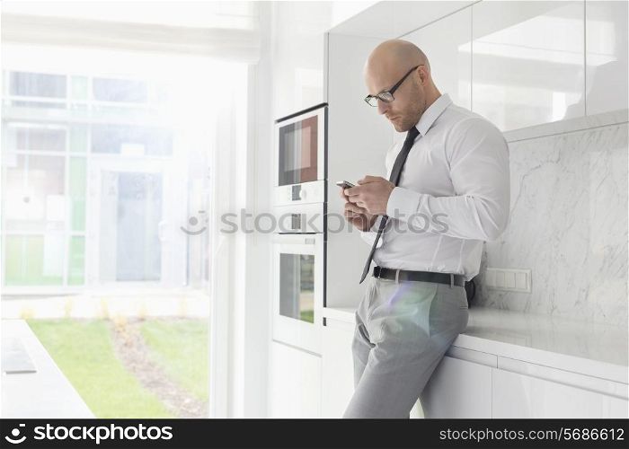 Side view of mid adult businessman using cell phone at home