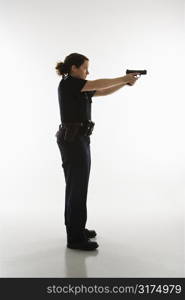 Side view of mid adult Caucasian policewoman standing and aiming handgun.