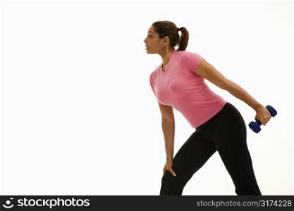 Side view of mid adult multiethnic woman wearing pink shirt exercising with dumbbell.