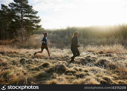Side view of mother and sons running on frosty grassland