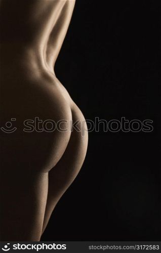 Side view of nude Hispanic mid adult female back and buttocks.