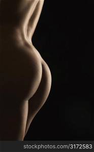 Side view of nude Hispanic mid adult female back and buttocks.