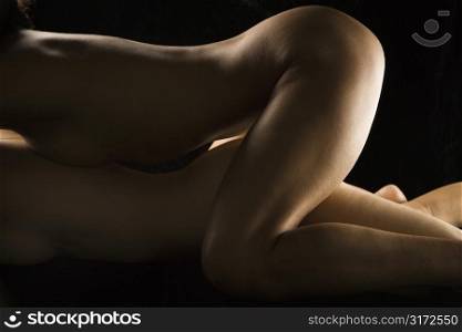 Side view of nude Hispanic woman lying on top of Caucasian women.