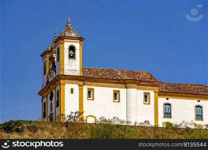 Side view of old and historic  church in 18th¢ury colonial arχtecture on top of the hill in the city of Ouro Preto in Minas Gerais, Brazil with the mountains behind. Side view of old and historic church in 18th¢ury colonial arχtecture at Ouro Preto city