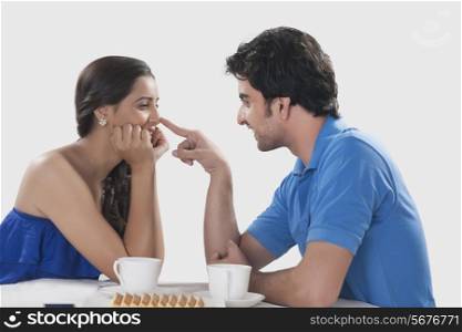 Side view of playful couple having coffee over white background