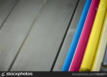 Side view of rollers in a set of laser printer color cartridges on gray wooden background