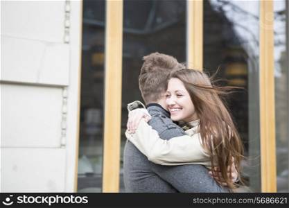 Side view of romantic couple hugging outside cafe