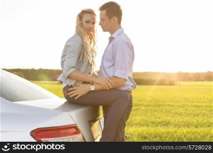 Side view of romantic young couple by car at countryside