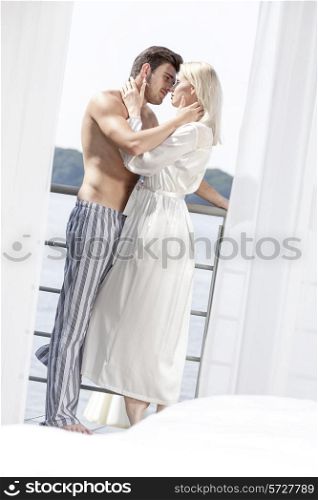 Side view of romantic young couple in sleepwear spending quality time on hotel balcony